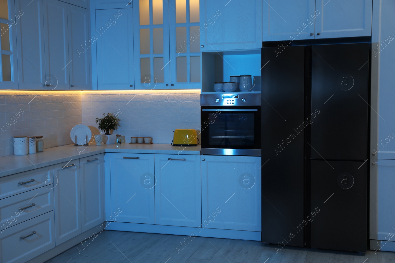 Photo of Stylish kitchen interior with modern refrigerator at night