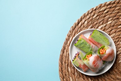 Plate of different delicious spring rolls wrapped in rice paper on light blue background, top view. Space for text