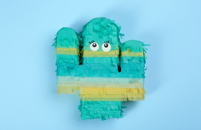 Photo of Bright cactus pinata on light blue background, top view
