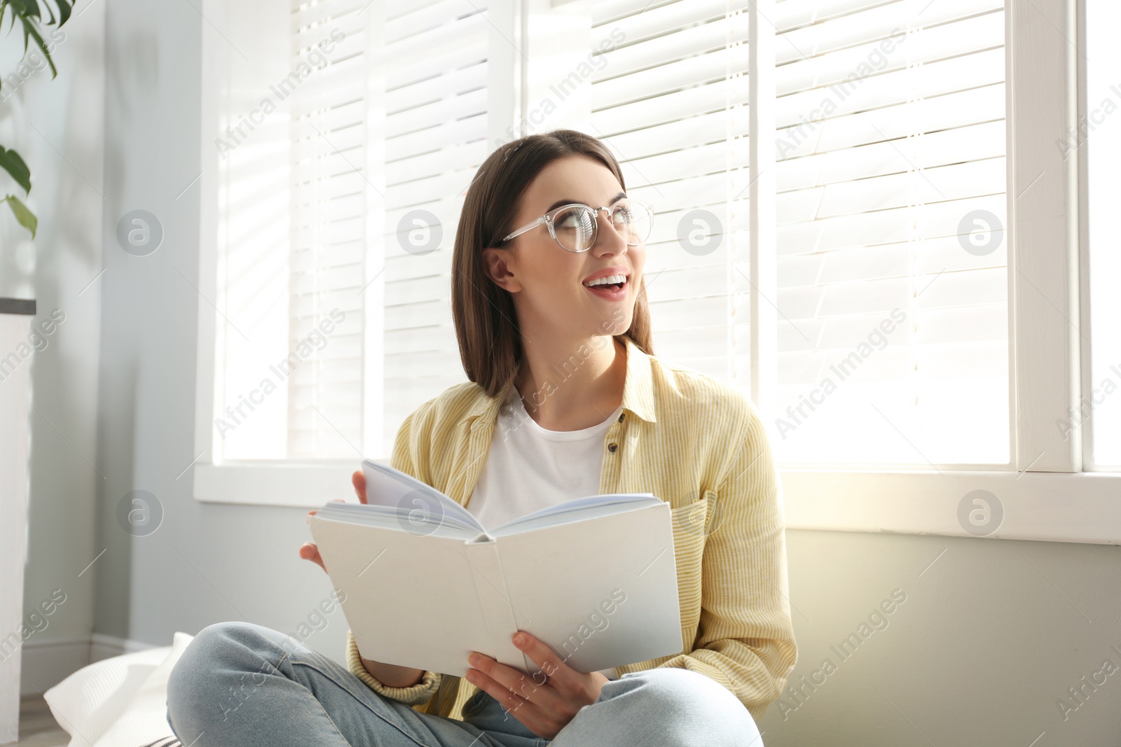 Photo of Beautiful young woman reading book at home