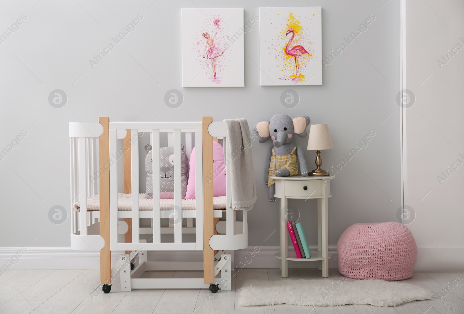 Photo of Children's room with comfortable crib and pictures on grey wall. Interior design