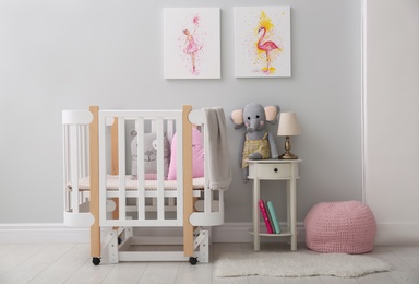 Children's room with comfortable crib and pictures on grey wall. Interior design