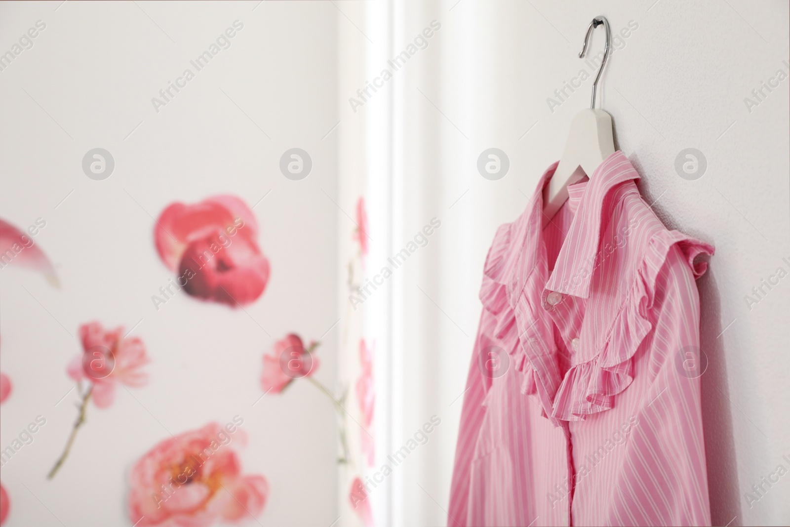 Photo of Pink shirt hanging on wall indoors. Space for text