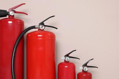 Photo of Set of fire extinguishers on beige background, space for text