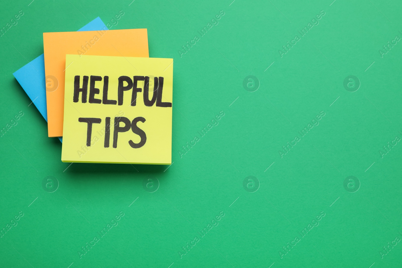 Photo of Paper note with phrase Helpful Tips on green background, top view. Space for text