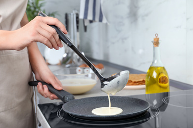 Photo of Woman cooking delicious thin pancakes on induction stove, closeup