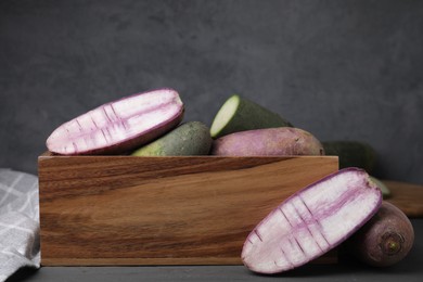 Photo of Purple and green daikon radishes in crate on black wooden table