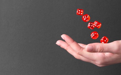 Photo of Woman throwing game dices on black background, closeup. Space for text