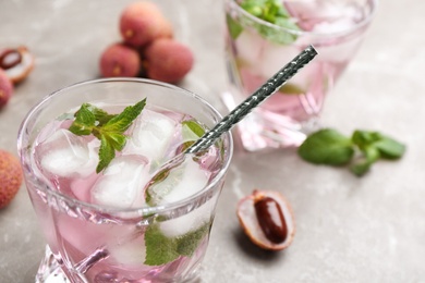 Lychee cocktail with mint and ice on grey table, closeup