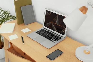 Photo of Cozy workspace with laptop, smartphone and lamp on wooden desk at home