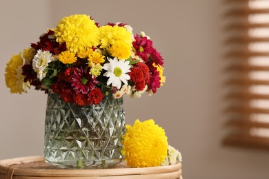 Photo of Bouquet of beautiful chrysanthemum flowers on wicker table indoors, space for text