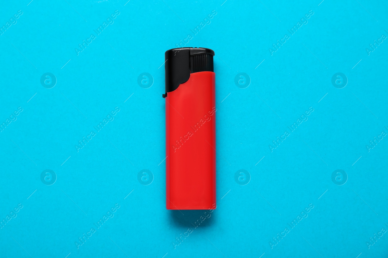 Photo of Red plastic cigarette lighter on light blue background, top view