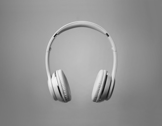 Stylish modern headphones with earmuffs on color background