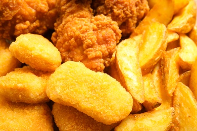 Tasty nuggets and deep fried chicken pieces as background, closeup