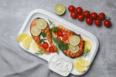 Tasty grilled salmon steaks and ingredients on light grey table, flat lay