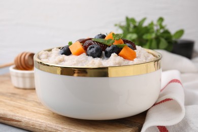 Delicious barley porridge with blueberries, pumpkin, dates and mint in bowl on table, closeup