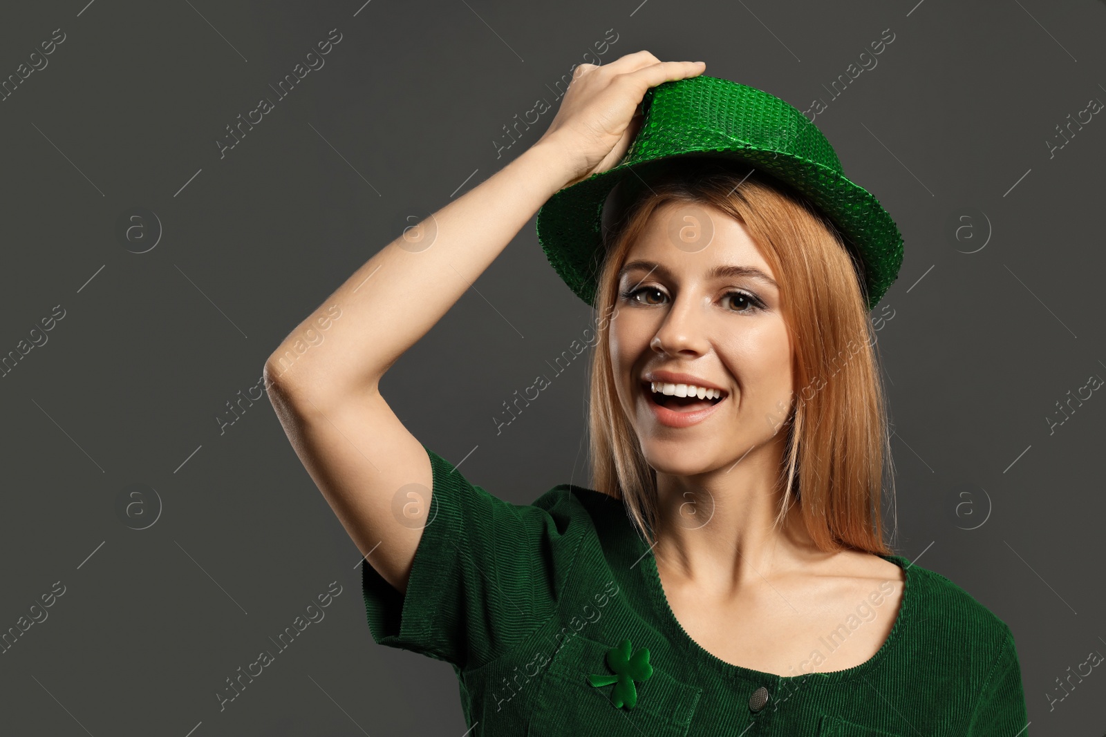 Photo of Young woman in green outfit on grey background. St. Patrick's Day celebration