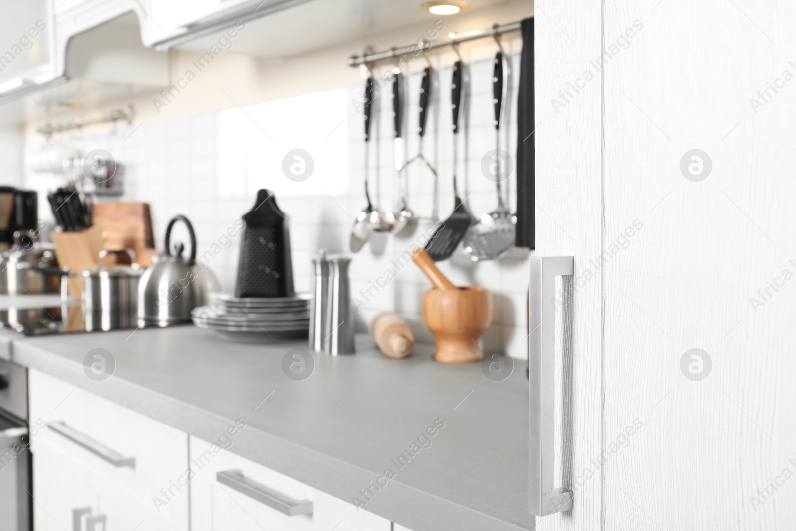 Photo of Blurred view of different appliances, clean dishes and utensils on kitchen counter