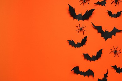 Flat lay composition with paper bats and spiders on orange background, space for text. Halloween celebration