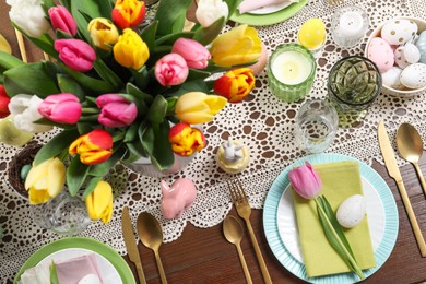 Festive table setting with beautiful flowers, flat lay. Easter celebration