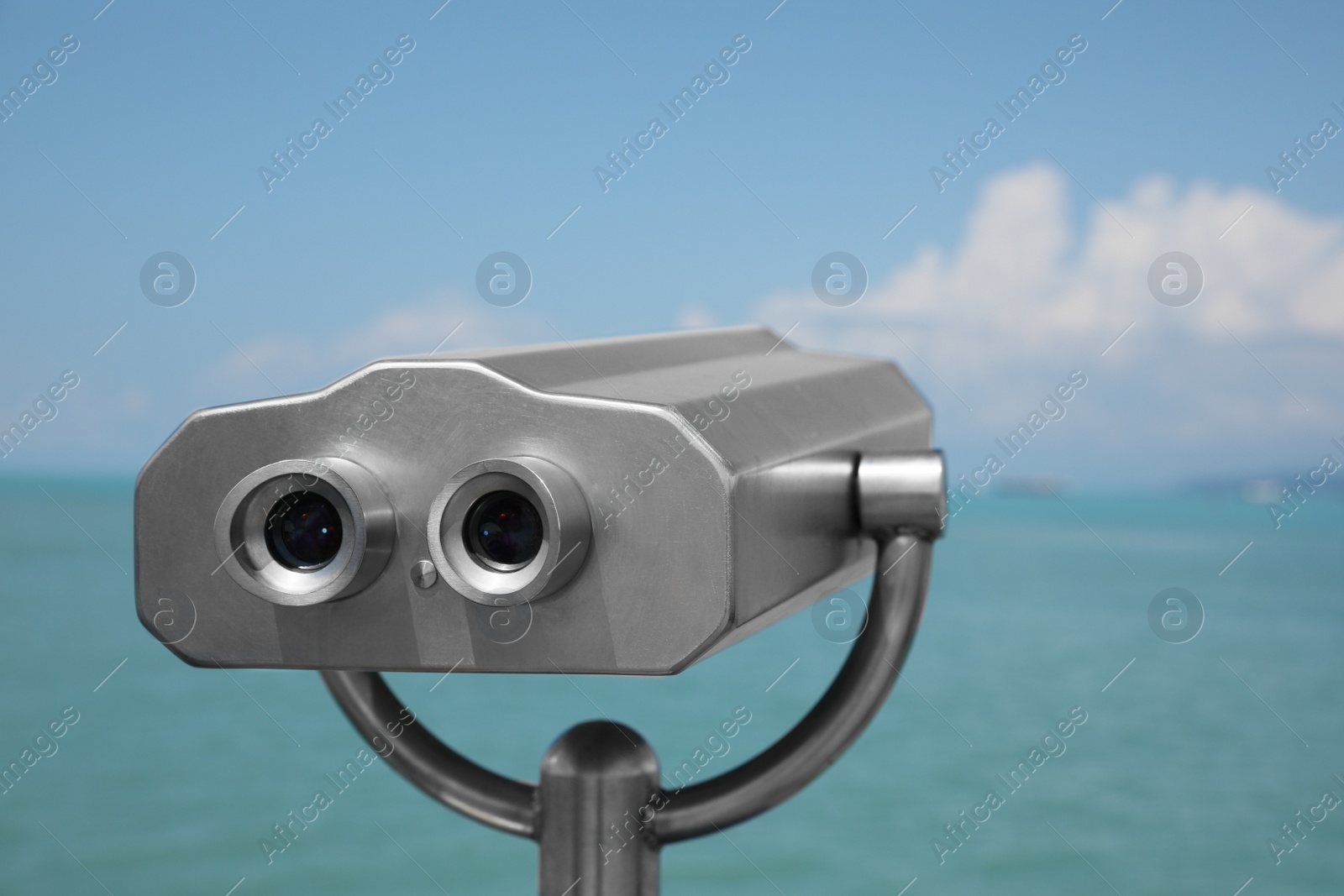 Photo of Metal tower viewer installed near sea. Mounted binoculars