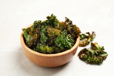 Photo of Tasty baked kale chips on grey marble table