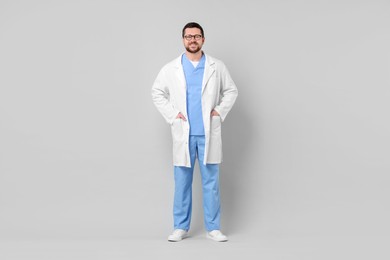 Photo of Full length portrait of smiling doctor on light grey background