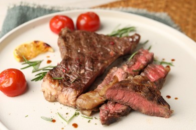 Photo of Delicious grilled beef steak, tomatoes and rosemary on plate, closeup