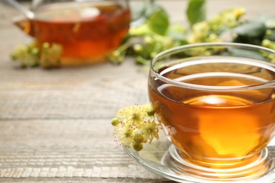 Photo of Cup of tea and linden blossom on wooden table, closeup. Space for text