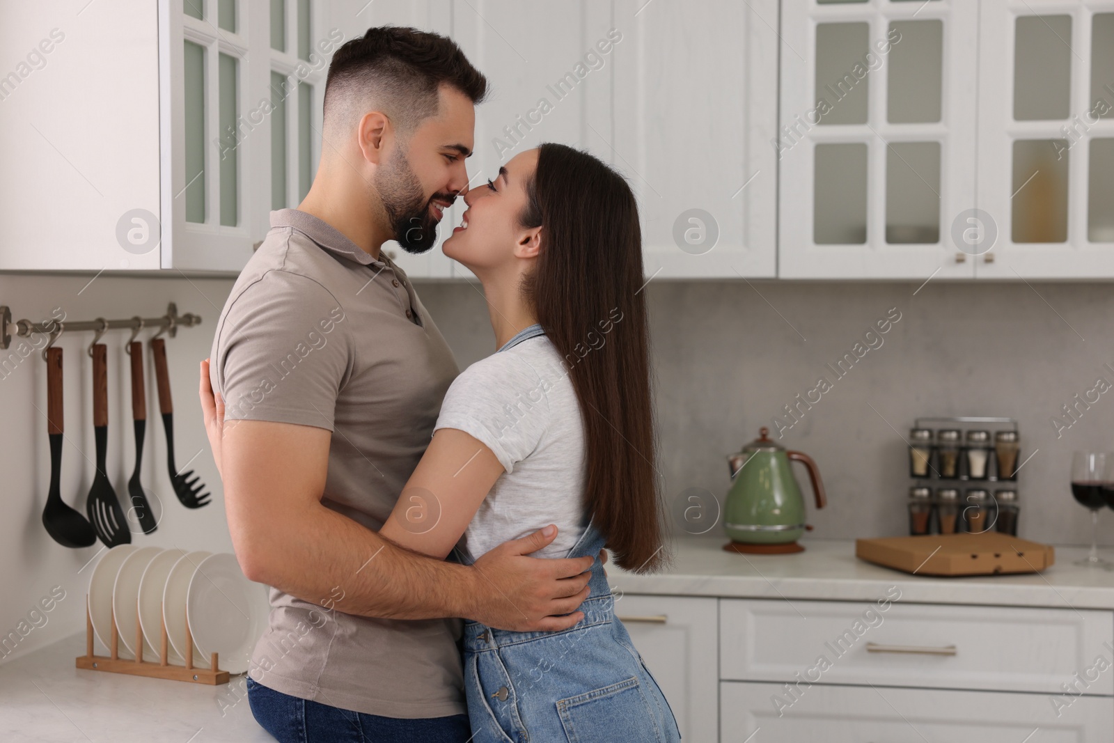 Photo of Affectionate couple hugging in kitchen. Space for text
