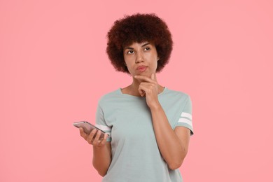 Photo of Thoughtful young woman with smartphone on pink background
