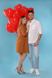 Lovely couple with heart shaped balloons on light blue background. Valentine's day celebration