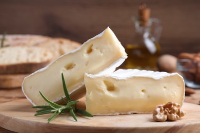 Tasty cut brie cheese with rosemary and walnut on wooden table
