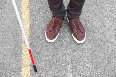 Photo of Blind person with cane crossing road, closeup