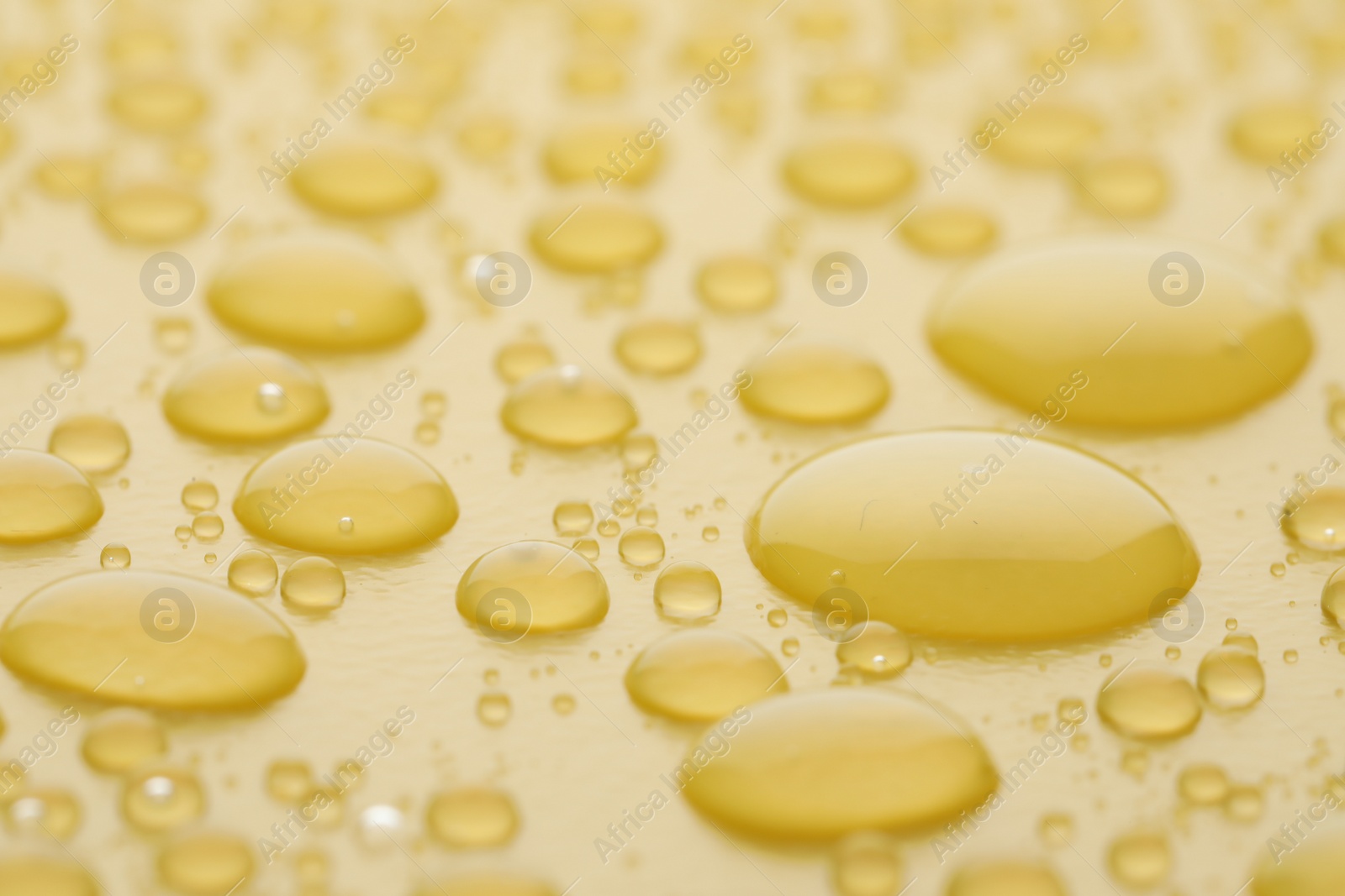 Photo of Water drops on yellow background, closeup view