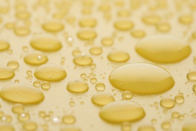 Water drops on yellow background, closeup view