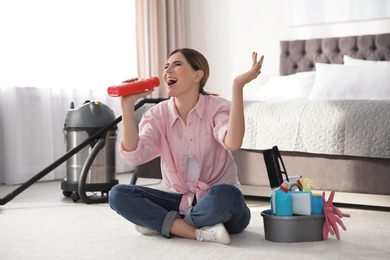 Happy woman having fun while cleaning bedroom