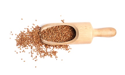 Scoop with uncooked buckwheat on white background, top view