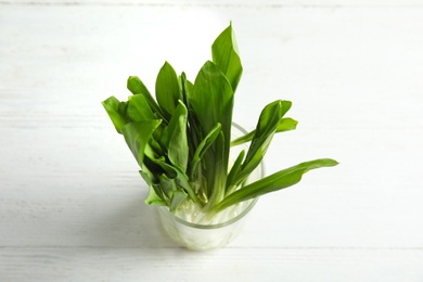 Photo of Glass of wild garlic or ramson on white wooden table, above view