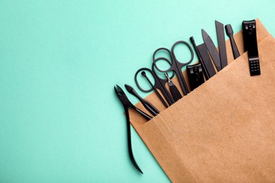 Photo of Manicure set in paper bag on turquoise background, top view. Space for text