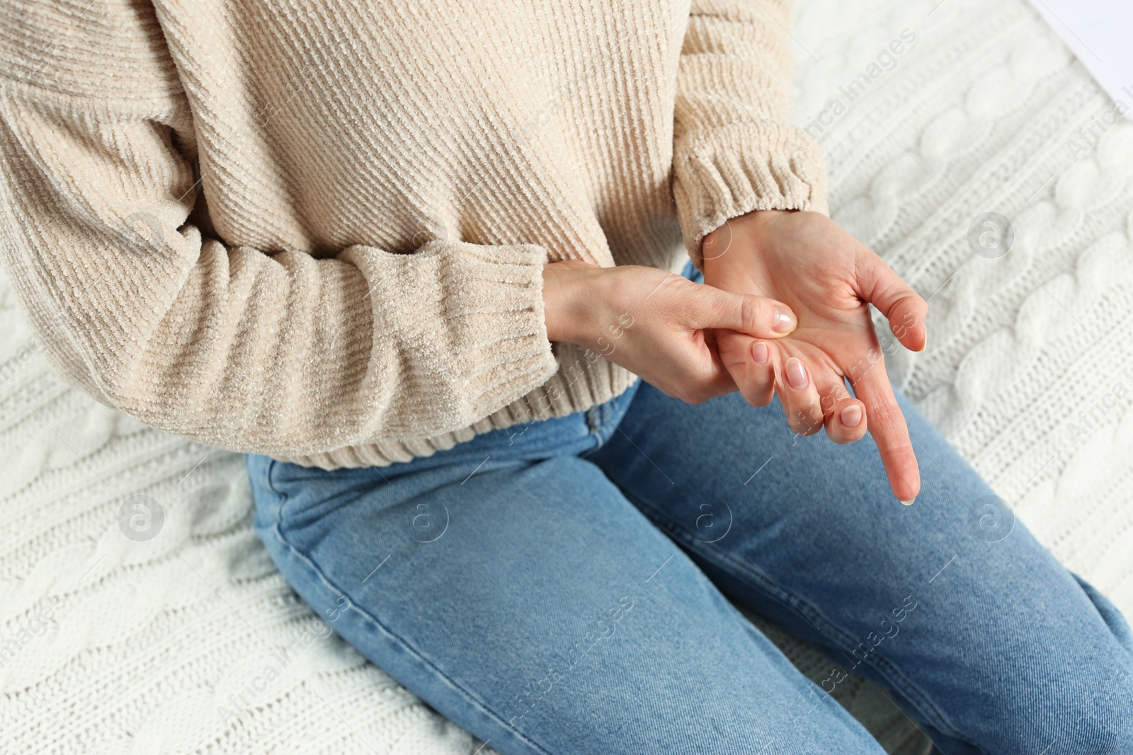 Photo of Woman suffering from trigger finger on bed, closeup