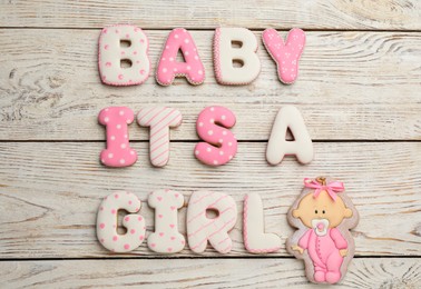 Photo of Baby shower party. Phrase It's A Girl made of cookies on white wooden background, flat lay