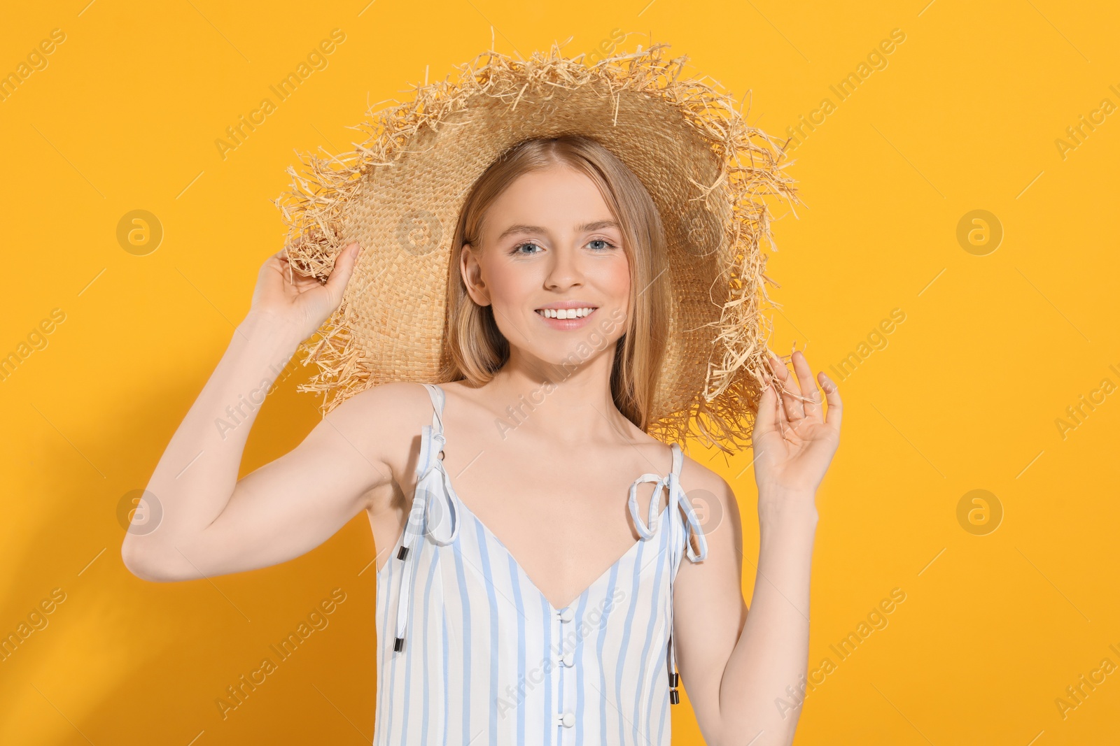 Photo of Beautiful young woman in straw hat on orange background