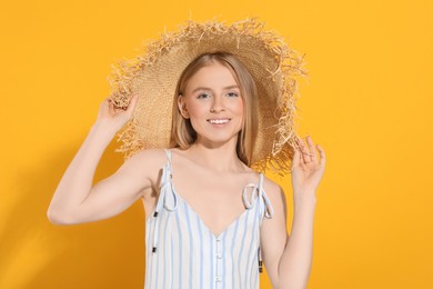 Photo of Beautiful young woman in straw hat on orange background