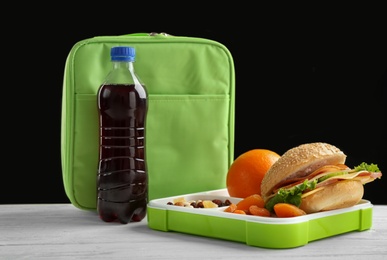 Photo of Lunch box with appetizing food and bag on table