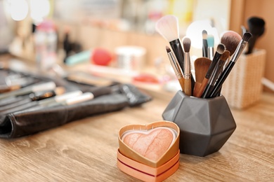 Holder with makeup brushes on table