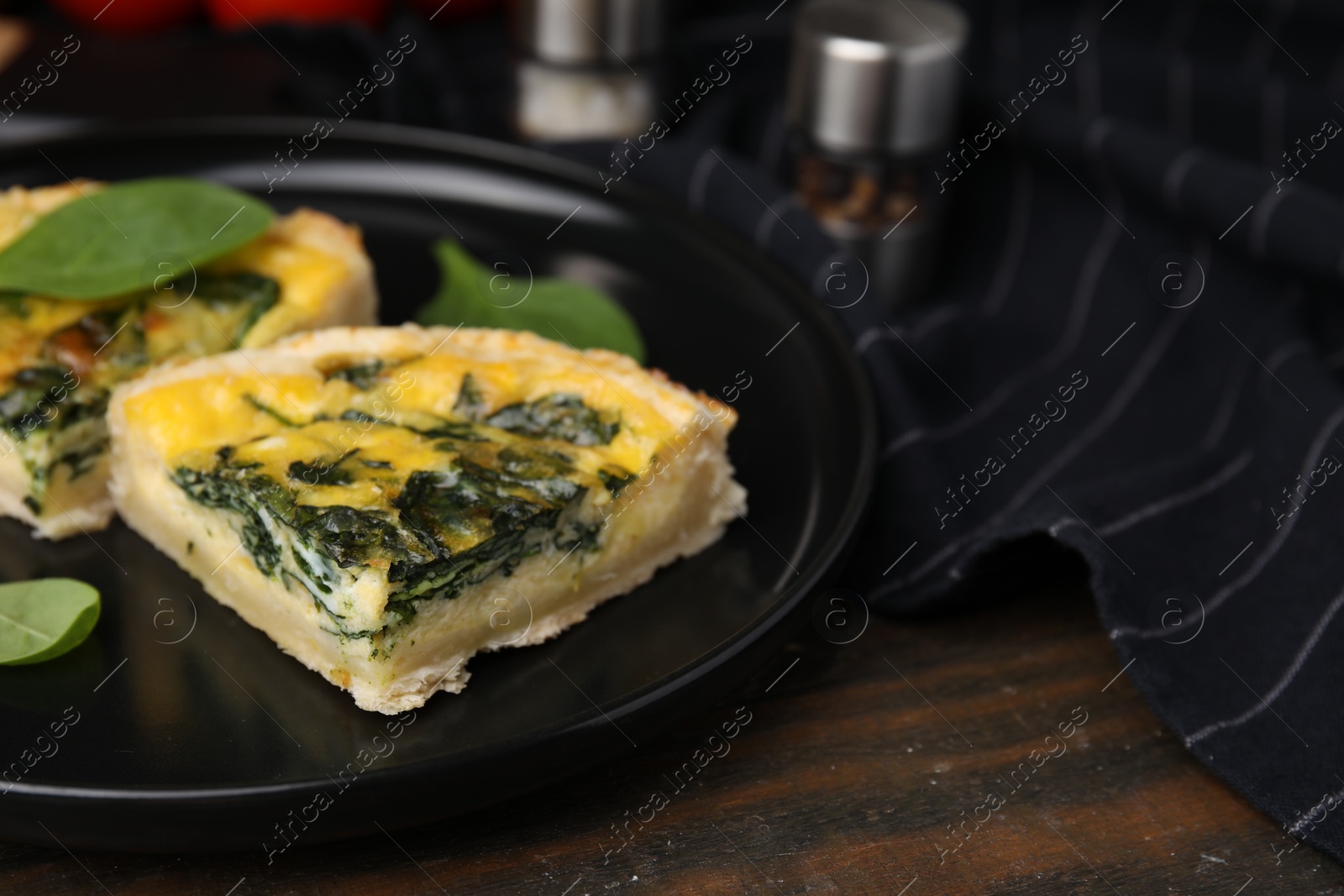 Photo of Pieces of delicious pie with spinach on wooden table, closeup. Space for text