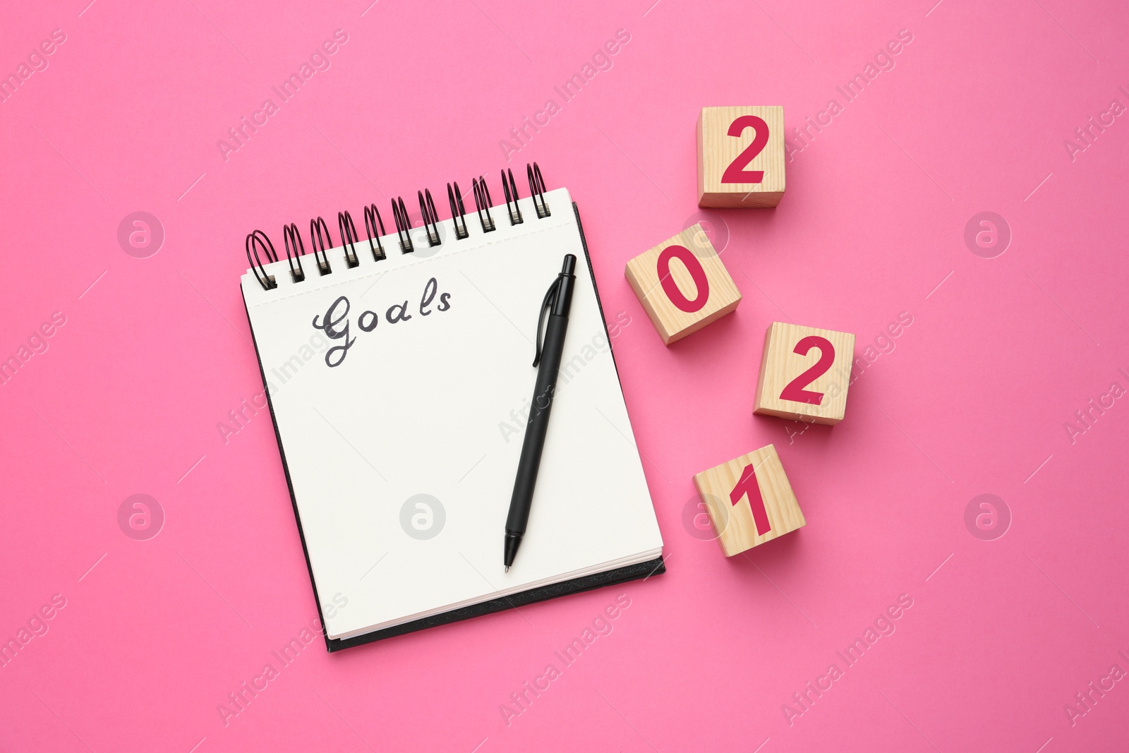 Photo of Flat lay composition with notebook on pink background. Goals for New Year 2021