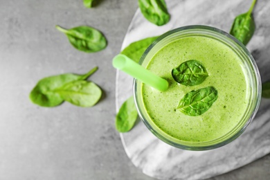 Flat lay composition with fresh green healthy spinach smoothie on grey table. Space for text