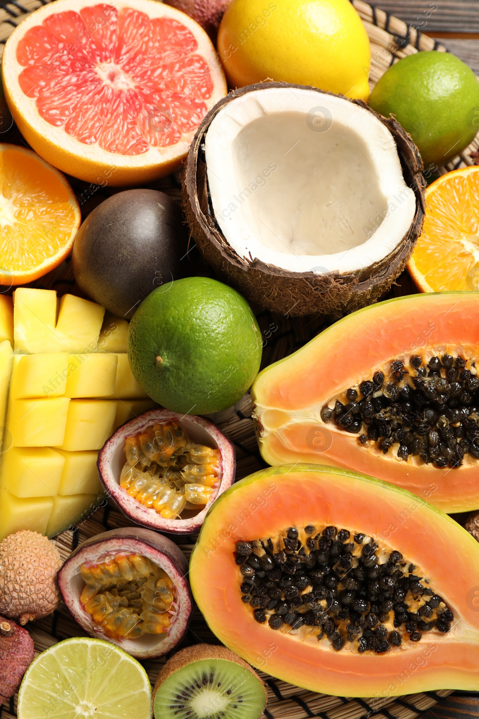 Photo of Fresh ripe papaya and other fruits on wicker mat, closeup view